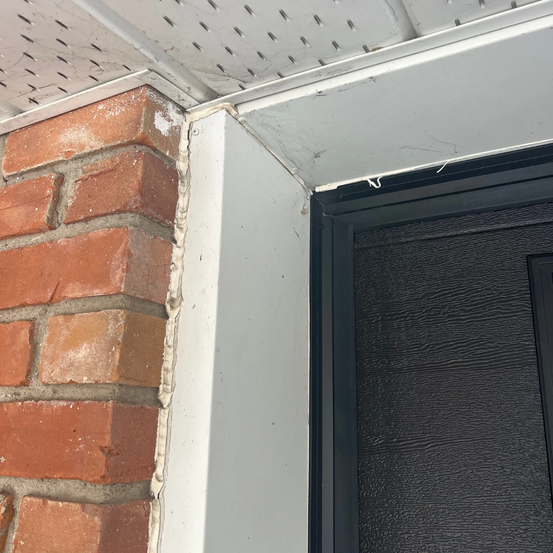 Before: weathered white trim surrounding a garage door beside brick
